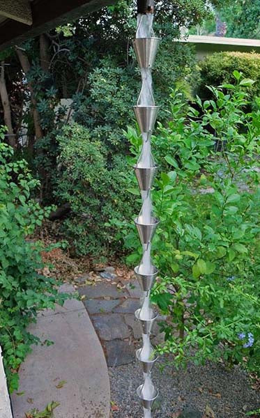Full length image of stainless colored Steel Cups Rain Chain on home with water running through cups